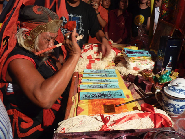 Phiong Cin Khiong, under possession by Het Lui Ciong Kiun, consecrating talismans at the annual temple birthday party, Singkawang, 2011. Photo by author.